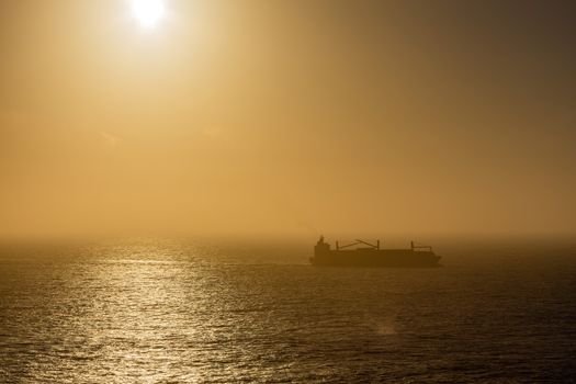 Top 5 Oportunități 'Ocean Jobs' pentru Brașoveni în Domeniul Maritim în Septembrie 2026 2 Silhouetted cargo ship navigating through misty ocean waters during sunrise.
